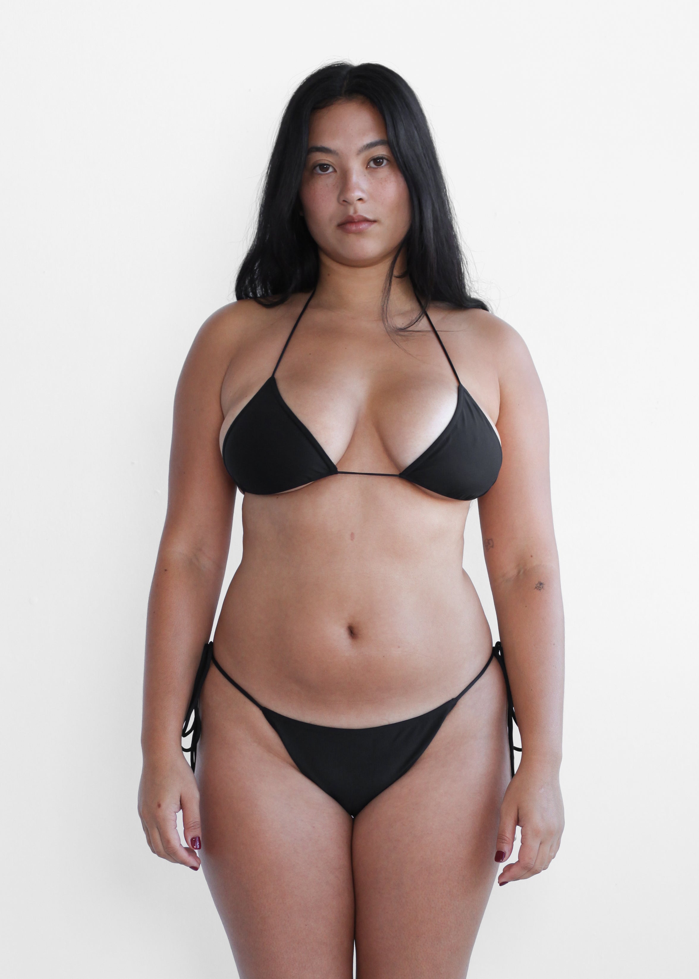 Size inclusive women's black triangle halter bikini top and tie-side bottoms with silver hardware, back view
